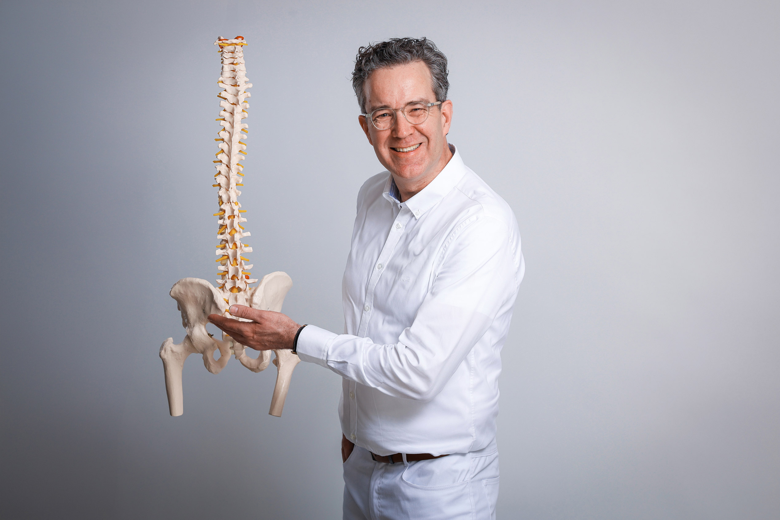 Dr. med. Stephan Meyer-Schwickerath mit Wirbelsäulenmodell – Praxis für Allgemeine Orthopädie und Wirbelsäulenorthopädie